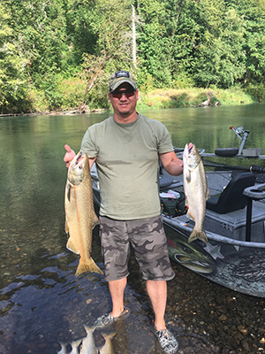 Fisherman with Salmon and Cutthroat Trout at River Bank